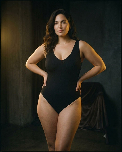 The Deep-V Sculpt Bodysuit on a model - plunging V-neckline, front three-quarter view, noir studio